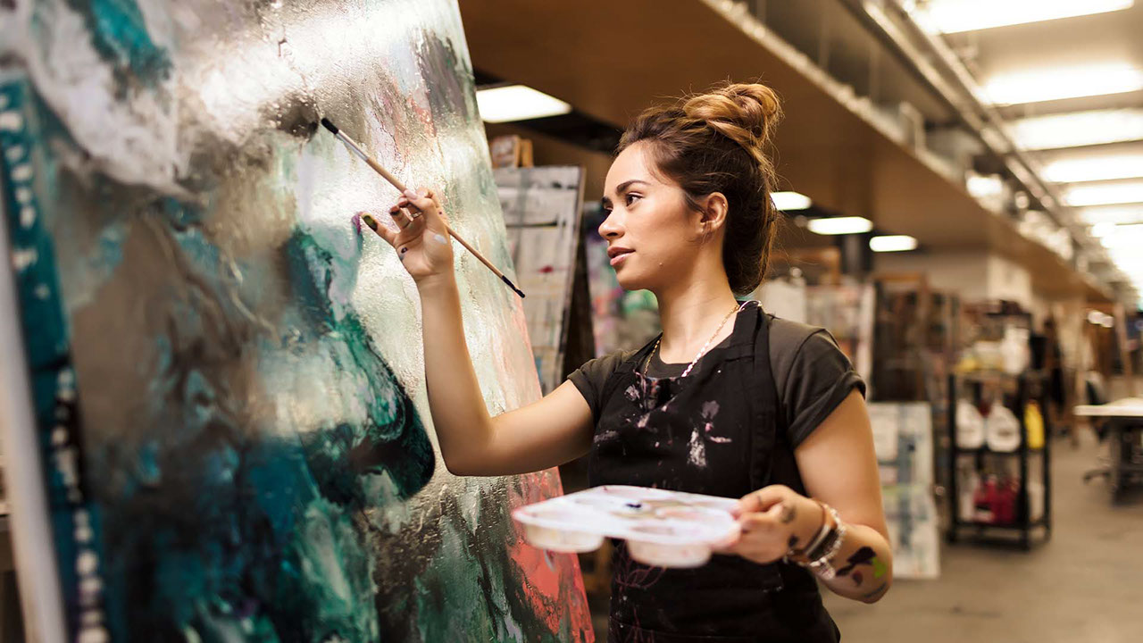 Photograph of a TAFE Queensland visual arts student painting in a studio